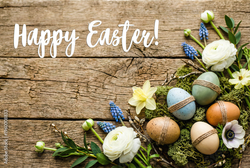 Natural holiday arrangement on a weathered wooden surface features spring flowers and a Happy Easter greeting text.