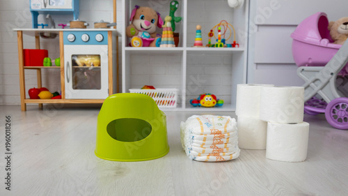 фотографія Potty training essentials: baby diapers, toilet paper rolls, and a green plastic potty