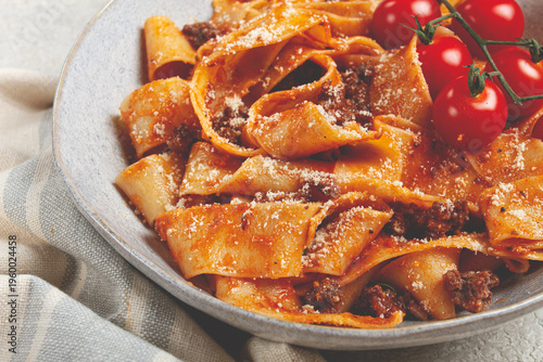 Foto pappardelle pasta with bolognese sauce, topped with parmesan cheese and cherry b