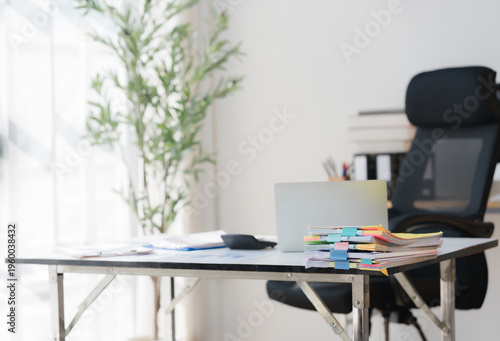 Modern Office Workspace: An organized workspace featuring a desk, chair, laptop, and office supplies bathed in natural light, evoking a sense of productivity and focus.
