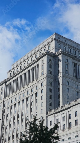 Low-angle view of a grand neoclassical courthouse or government building with stone columns. Majestic classical architecture symbolizing law, justice, and authority against a blue sky with clouds.