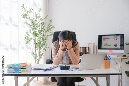 Overwhelmed: A person experiencing stress, anxiety, or emotional distress in an office environment. Depicted sitting at a desk and using a laptop with scattered files.