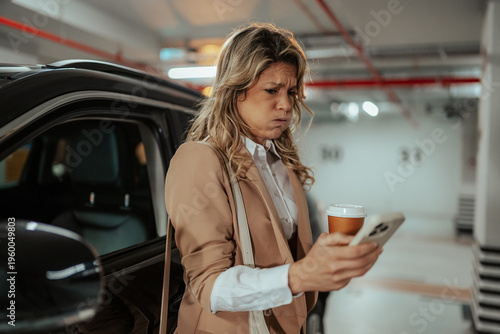 Fotografija Stressed businesswoman receiving bad news on smartphone in parking garage, feeli