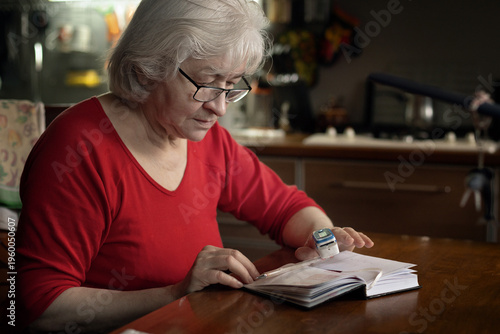An elderly woman uses a pulse oximeter at home to measure oxygen saturation.