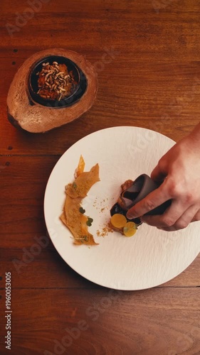 dishes of haute cuisine presentation serving details in dishes. chef hands put greens flowers sauce on plate. close up white plate in restaurant. food in Michelin restaurant. modern cooking technology