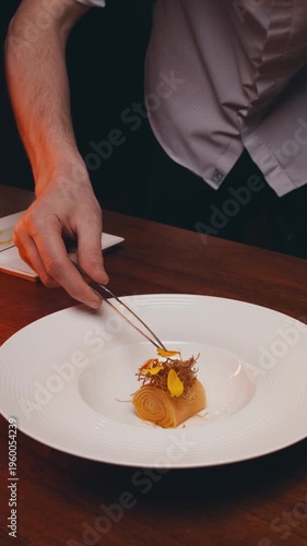 dishes of haute cuisine presentation serving details in dishes. chef hands put flowers ice cream on plate. close up white plate in restaurant. food in Michelin restaurant. modern cooking technology