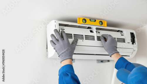 Technician installing air conditioner unit on white wall. Man worker using spirit level tool for precise indoor mounting. Professional HVAC climate control system maintenance concept.