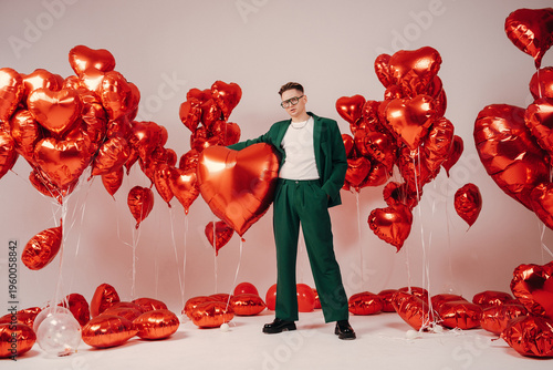 Man wearing white shirt among shiny festive balloons and shapes
