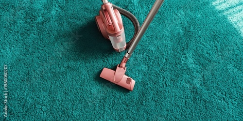 Compact pink canister vacuum on teal carpet overhead view showing hose and head during cleaning session, domestic floor care concept