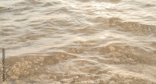 Abstract nature background composed of beige sunlit water waves
