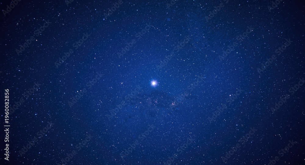 Fototapeta premium Faraway planet illuminated by a vibrant blue sky filled with shimmering stars