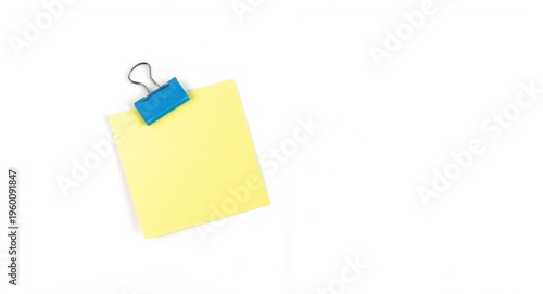 Blue magnetic clip affixing note on plain white backdrop with copy space and colorful pinboard design