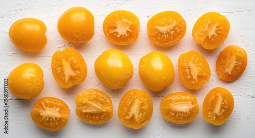 Freshly harvested yellow tomatoes separated on a plain white textured surface