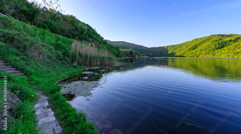 Fototapeta premium Beautiful lake with a green hill in the background