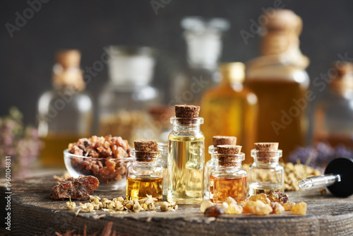 Selection of essential oils in glass bottles with frankincense, myrrh and herbs