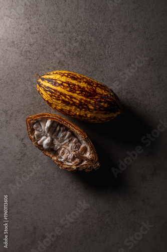 Mazorca de cacao entera sobre superficie de mármol negro con iluminación dramática