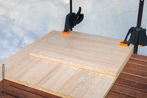 Fotografie Chipboard boards are glued and held together with two clamps.