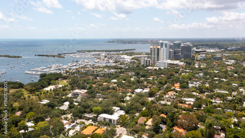 A sweeping drone shot showcases Coconut Grove’s tropical canopy, waterfront homes, and bustling marina along Miami’s coastline.