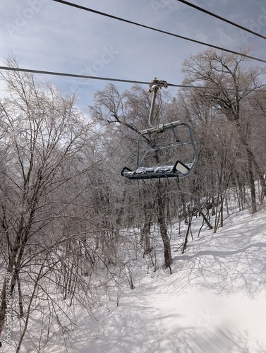 Skiing in winter - chairlift and ski slopes for skiing and snowboarding  between trees on a frosty day with beautiful views in  mountains. Ski resort after blizzard