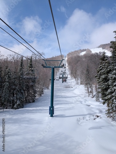 Skiing in winter - chairlift and ski slopes for skiing and snowboarding  between trees on a frosty day with beautiful views in  mountains. Ski resort after blizzard