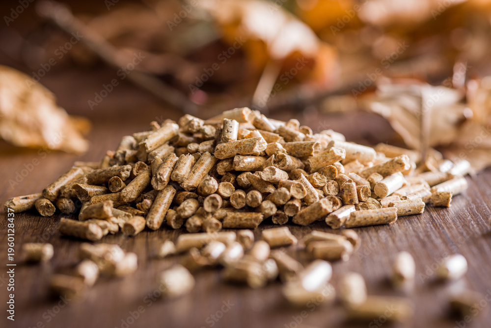 Obraz premium Wood Pellets Pile for Biofuel Heating and Renewable Energy Closeup on Rustic Wooden Surface