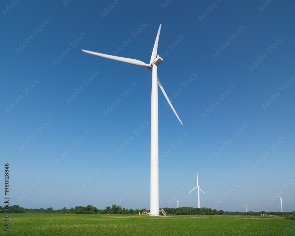 Fototapeta premium Wind Turbines in green summer field countryside scenery