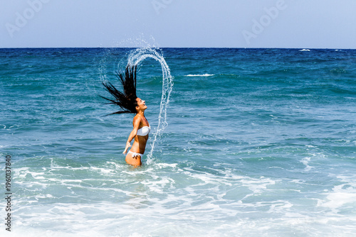 Stress free, freedom, wellness, success concept. Happy carefree stress free white bikini woman jumping splashing of success joy in ocean waters of peaceful beach. Travel, vacation, success, freedom