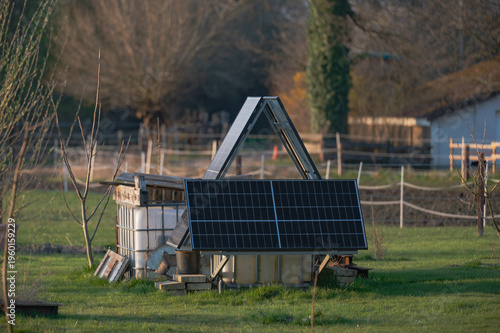 Obraz na plátně DIY solar panel system installed in backyard garden,  photovoltaic panels mounted on simple wooden structure supported by water containers