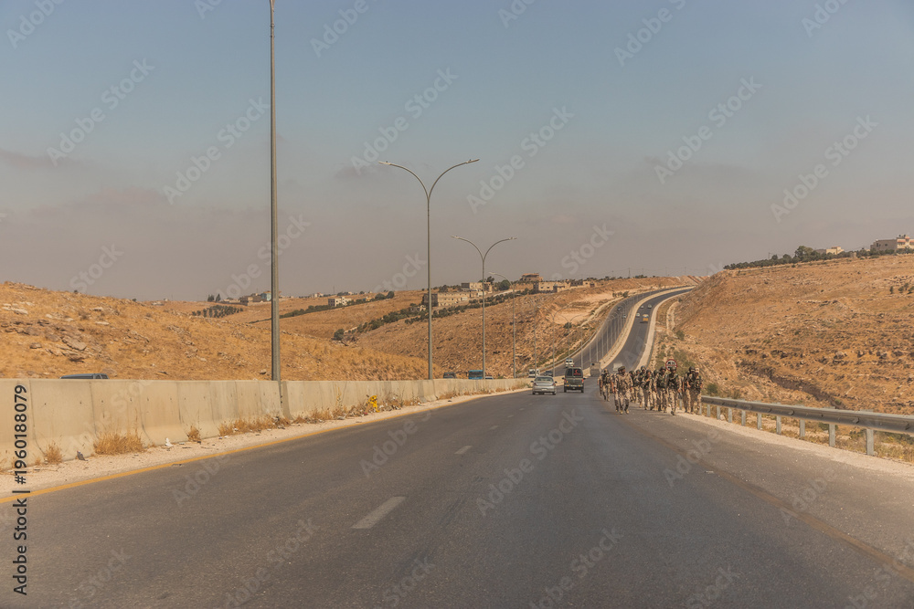 Fototapeta premium IRBID, JORDAN - JULY 17, 2022: Soldiers marching at Irbid Ring Road, Jordan