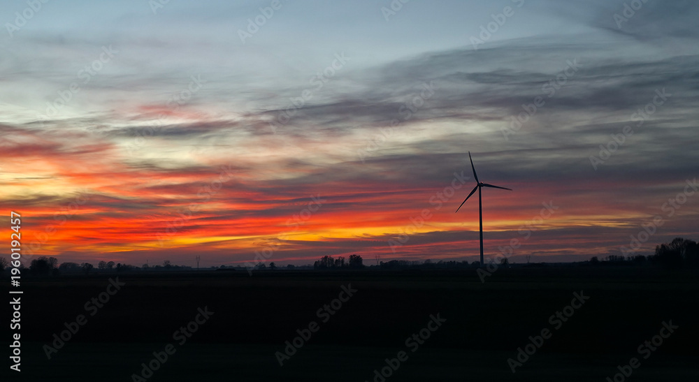 Fototapeta premium Wind turbines against the backdrop of a colorful picturesque sunset. Alternative eco-friendly sources of electricity