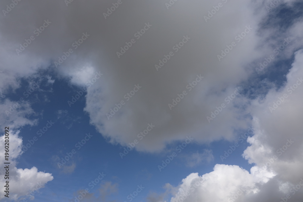 Obraz premium Beautiful blue sky with white fluffy cumulus clouds. Summer day background. High resolution nature texture suitable for wallpaper or design overlays