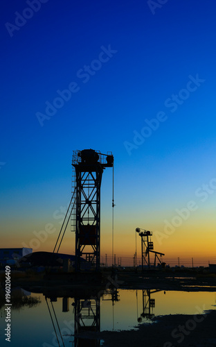 The oil pumping unit is operating in the evening outdoors