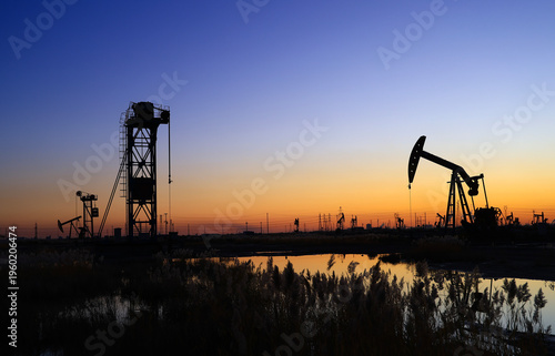 The oil pumping unit is operating in the evening outdoors