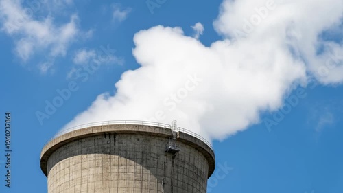 Clean energy nuclear cooling tower releasing steam plume against blue