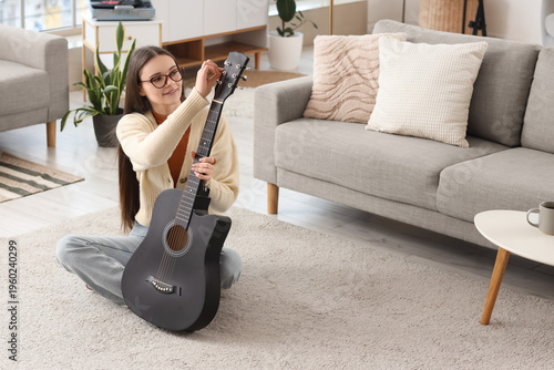 Young girl tuning guitar st...