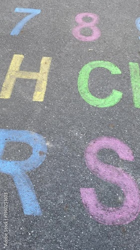 alphabet and numbers are drawn with color paint on a children's asphalt playground to learn and play. the alphabet educational element learning space. Vertical video
