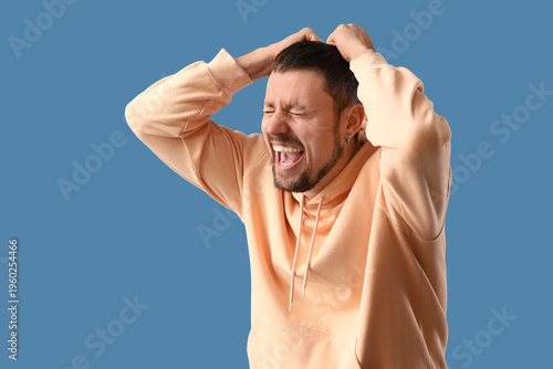 Screaming young man on blue...