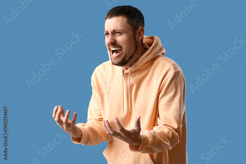 Screaming young man on blue...