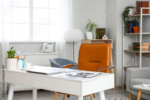 Interior of psychologist's cabinet with test pictures, notebook and laptop on workplace