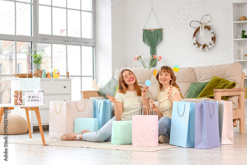 Foto Happy young women with paper shopping bags and decor for Easter at home