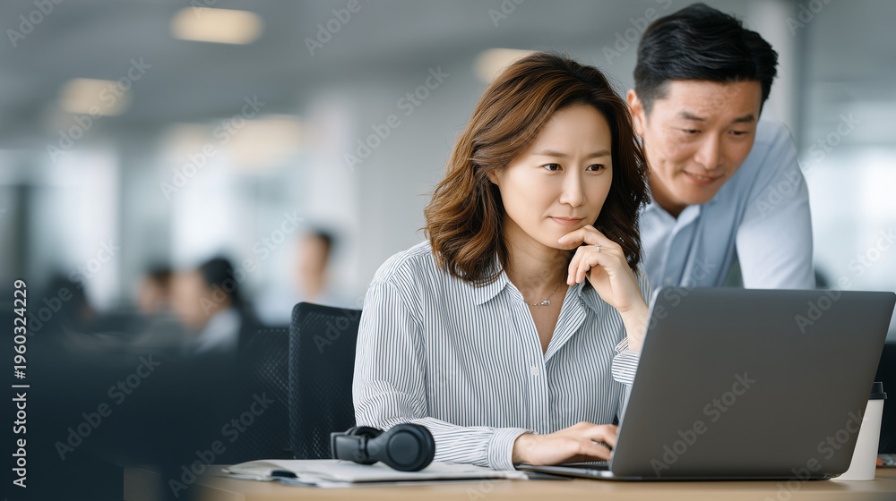 Fototapeta premium Focused Collaboration: A professional woman and man engage in a collaborative work session, absorbed in their task, and enhancing their analytical thinking
