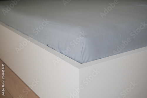Fotografie Soft bed sheet draped over a modern bed frame in a room