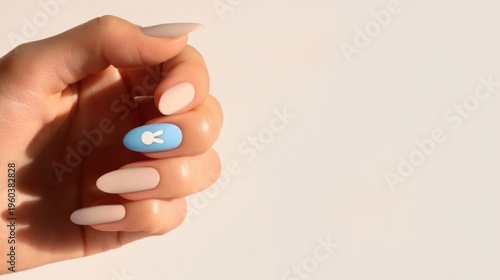 A close-up of a woman's hand with long, almond-shaped nails. The nails are painted in a light pink shade, with one nail featuring a blue design of a fish.