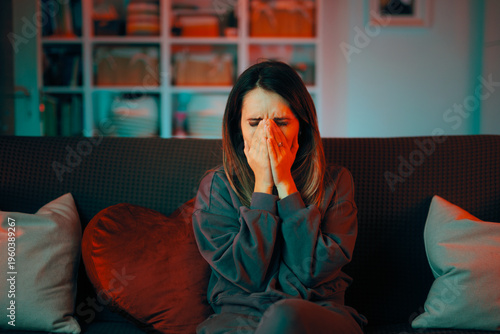 Upset Woman Covering her Face with her Hands. Woman in distress sitting o a couch, covering her face, keeping her eyes closed