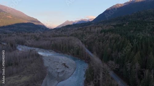 Aerial View of a Serene River, Forest, and Winding Road Amidst Majestic Mountains in British Columbia, Canada