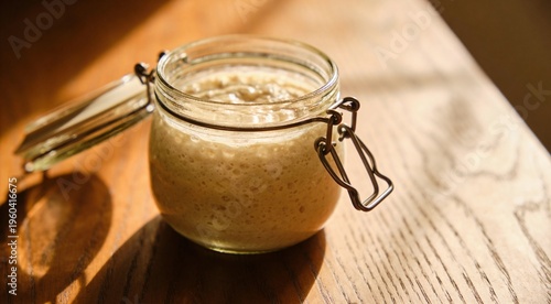 Close-up of bubbly sourdough starter in a jar on a wooden table