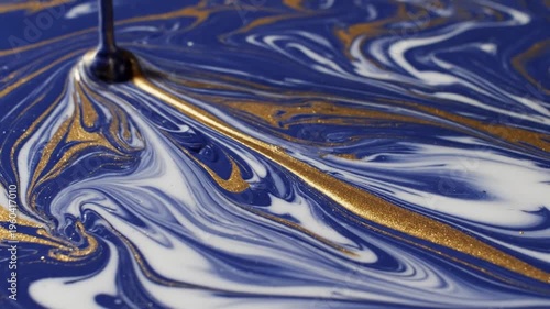 Swirling blue and gold liquid creating rippling patterns in a puddle