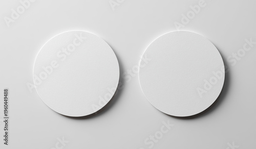 Two white round paper coasters mockup top view on minimal gray background