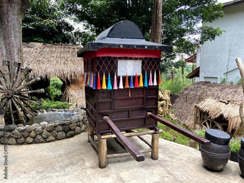Billede på lærred raditional Korean Palanquin Display

A dark wooden palanquin with a curved roof and colorful tassels, historically used by royalty or the upper class