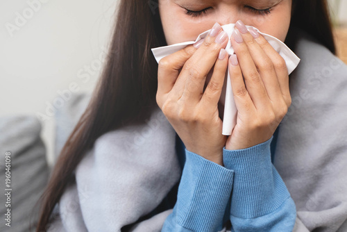 Obraz na plátne Sick in winter season common cold disease concept, Young woman have a runny nose and flu using tissue to blow her nose on the sofa during winter